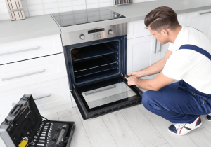 Young-man-repairing-oven-in-kitc